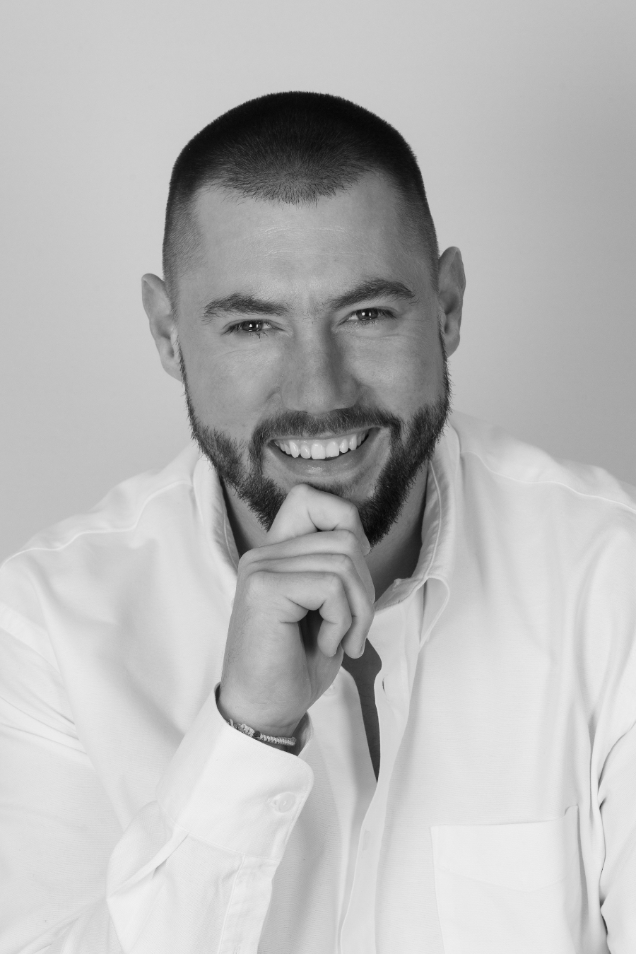 photo studio d'un beau jeune homme souriant, une main sous son menton