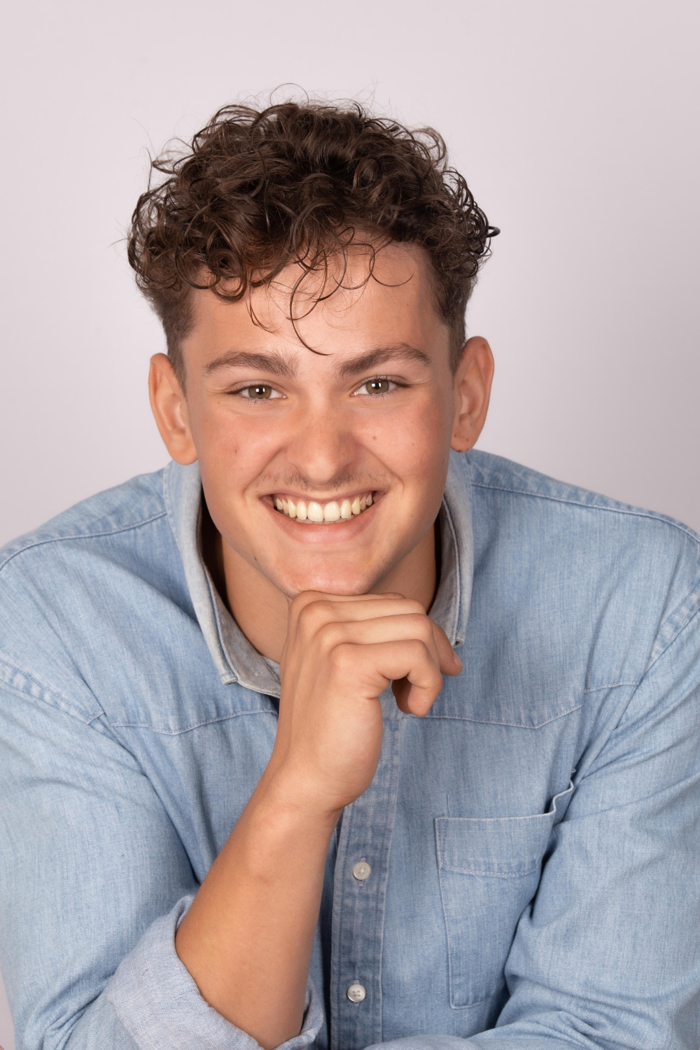 portrait d'un jeune homme souriant, main repliée sous son menton.