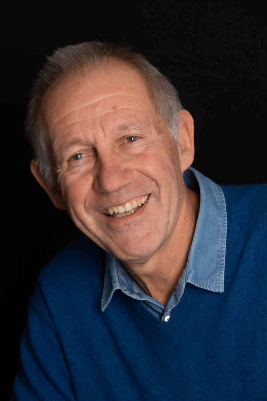 père de famille souriant en chemise et pull bleu