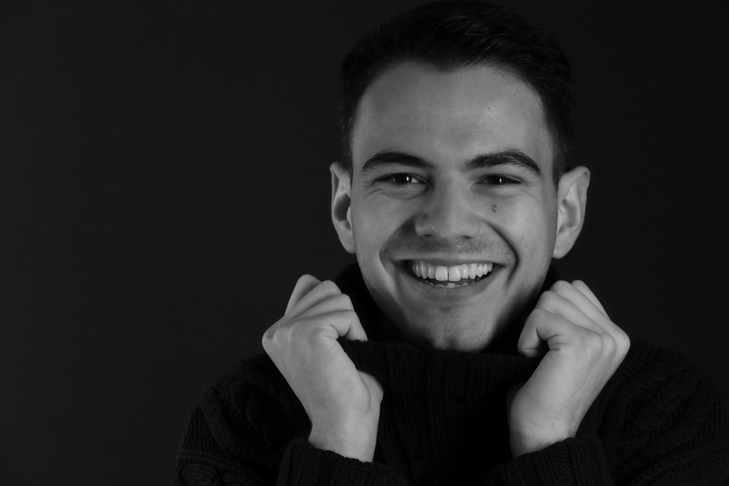 séance image de soi noir et blanc cadeau de noël d'un jeune homme brun souriant en col roulé