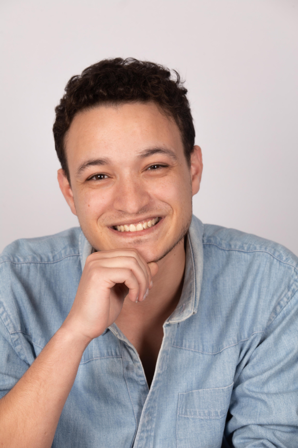 photo de face d'un jeune homme en chemise bleue, une main sous le menton